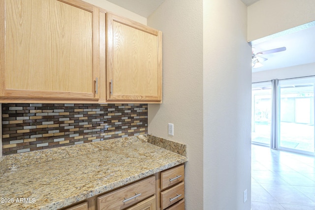 kitchen with light tile patterned floors, decorative backsplash, a ceiling fan, light stone counters, and light brown cabinets