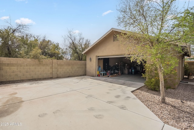 view of side of property featuring an outbuilding, fence, and stucco siding