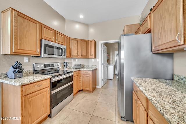 3131 E Legacy Dr Unit 1032, Phoenix, AZ 85042 - kitchen with appliances with stainless steel finishes, separate washer and dryer, light tile patterned floors, and light stone counters