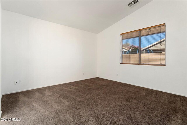 carpeted spare room featuring vaulted ceiling