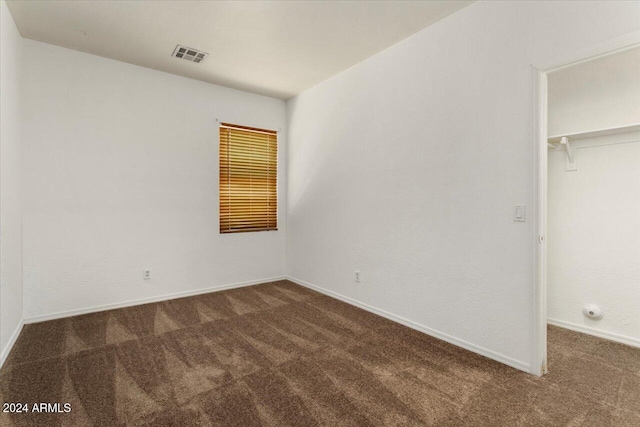 unfurnished bedroom featuring dark colored carpet, a spacious closet, and a closet