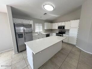 kitchen with white cabinetry, a kitchen island, lofted ceiling, and appliances with stainless steel finishes