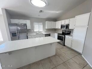 kitchen featuring white cabinetry, sink, stainless steel appliances, a kitchen island, and light tile patterned flooring