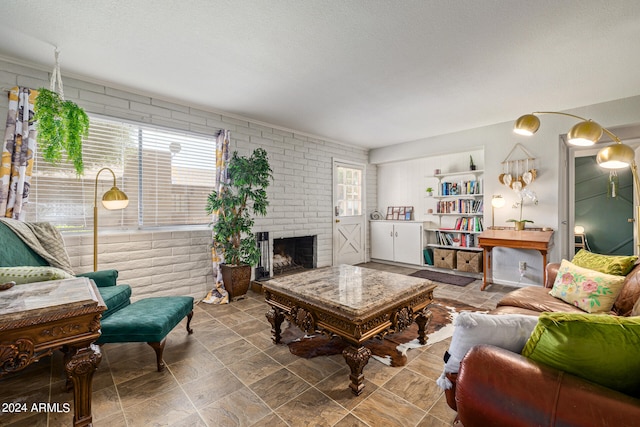 living room featuring a fireplace, brick wall, and a textured ceiling