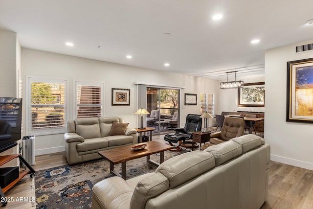 living room with an inviting chandelier and light wood-type flooring