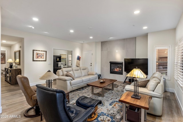 living room with a tiled fireplace and light hardwood / wood-style floors