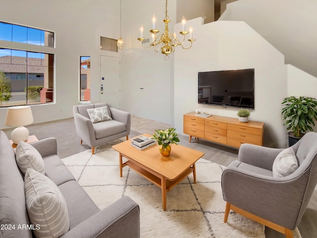 living room with light hardwood / wood-style floors, high vaulted ceiling, and an inviting chandelier