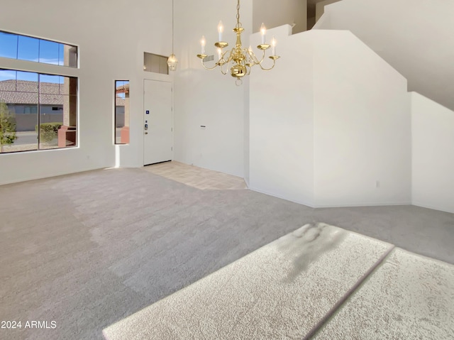 carpeted empty room with a chandelier and high vaulted ceiling