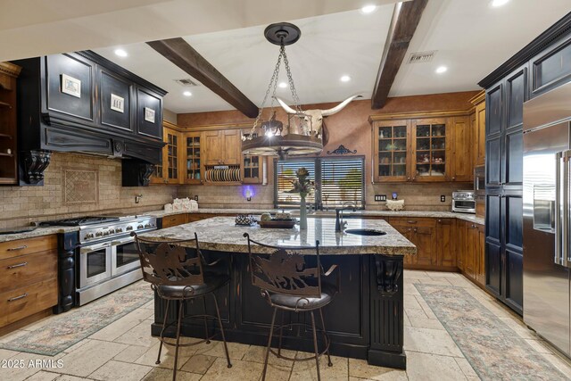 21230 S 156th St, Gilbert, AZ 85298 - kitchen featuring high end appliances, stone tile flooring, beamed ceiling, brown cabinetry, and recessed lighting