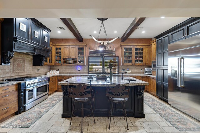 21230 S 156th St, Gilbert, AZ 85298 - kitchen with premium appliances, stone tile flooring, brown cabinets, a sink, and decorative backsplash
