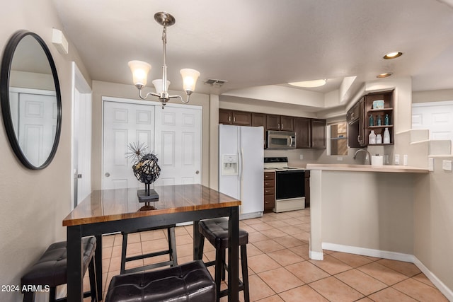 kitchen featuring kitchen peninsula, hanging light fixtures, dark brown cabinetry, sink, and white appliances