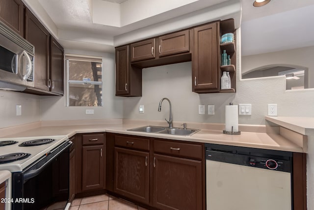 kitchen featuring dark brown cabinets, sink, light tile patterned floors, and white appliances