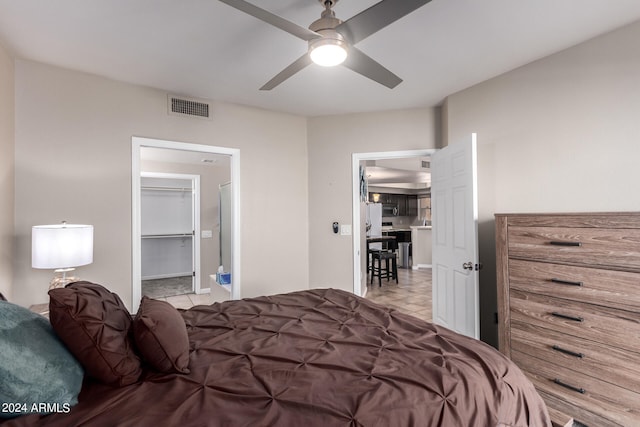 tiled bedroom with a walk in closet, a closet, and ceiling fan