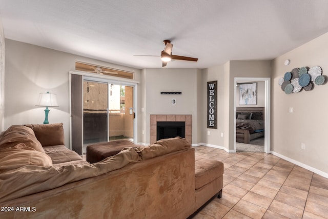 tiled living room with ceiling fan, a textured ceiling, and a tile fireplace