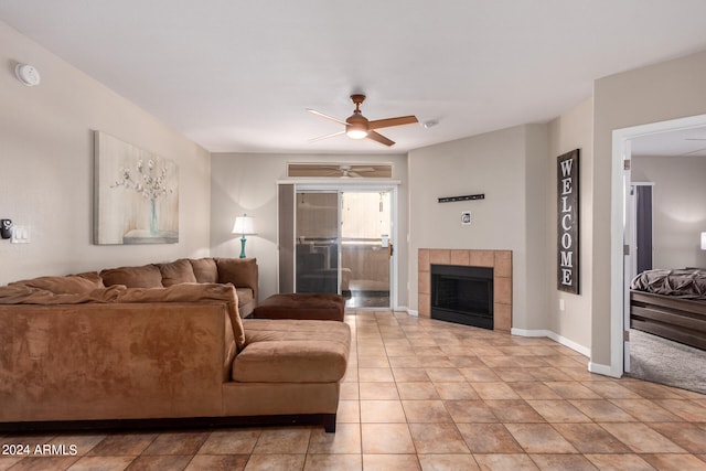 tiled living room with a tile fireplace and ceiling fan