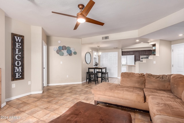 tiled living room featuring a textured ceiling, ceiling fan with notable chandelier, and vaulted ceiling