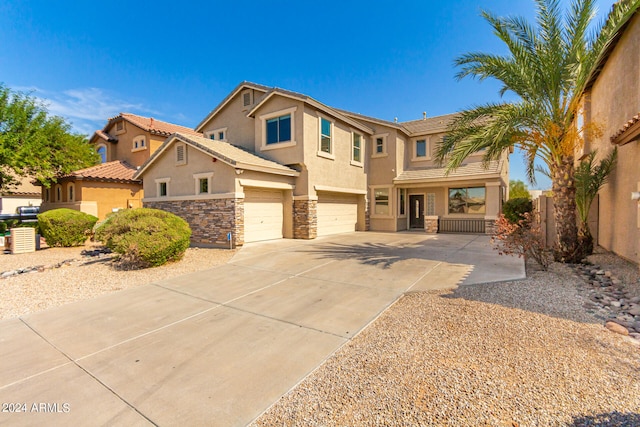 view of front of home with an attached garage, fence, stone siding, driveway, and stucco siding