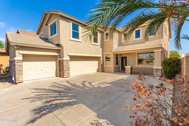 view of front of home with a garage, stone siding, concrete driveway, and stucco siding