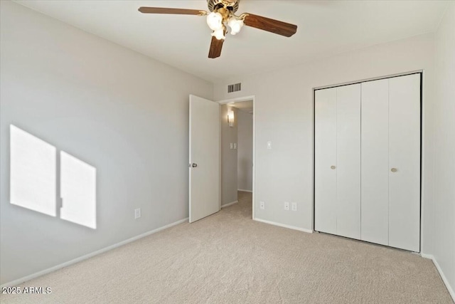 unfurnished bedroom featuring ceiling fan, light colored carpet, and a closet