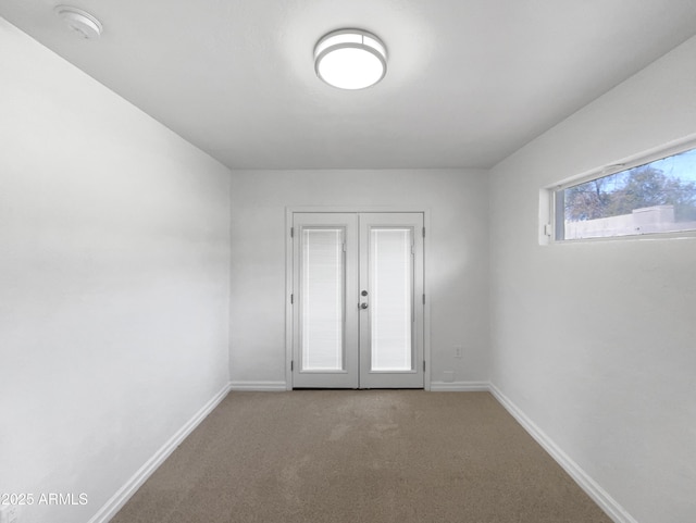 carpeted spare room featuring french doors