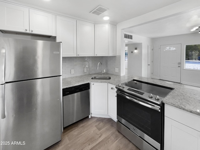 kitchen featuring stainless steel appliances, white cabinetry, sink, and light stone counters