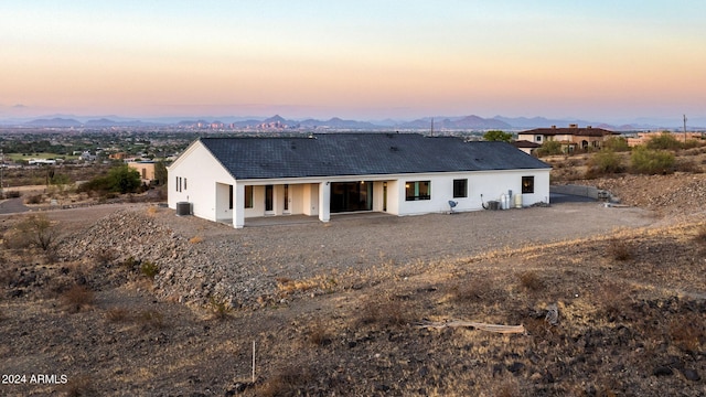 back house at dusk with a patio and a mountain view