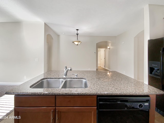 kitchen featuring sink, refrigerator with ice dispenser, pendant lighting, black dishwasher, and an island with sink