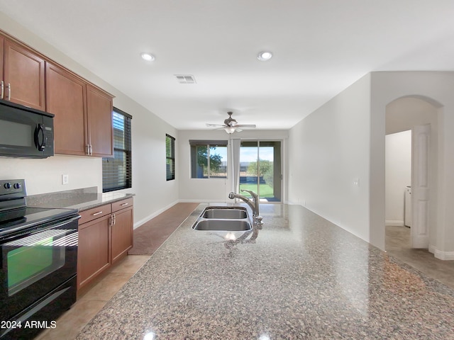 kitchen featuring black appliances, ceiling fan, dark stone countertops, and sink