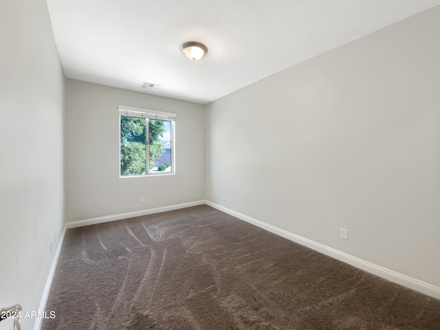 unfurnished room featuring dark carpet