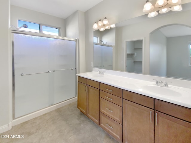 bathroom featuring a shower with door and vanity