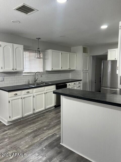 kitchen featuring white cabinets, dark wood-type flooring, decorative light fixtures, and stainless steel refrigerator