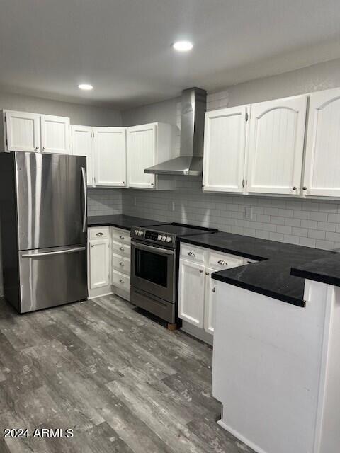 kitchen featuring appliances with stainless steel finishes, tasteful backsplash, wall chimney exhaust hood, and dark hardwood / wood-style floors