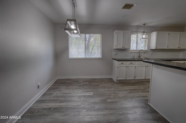 kitchen with white cabinets, sink, backsplash, decorative light fixtures, and wood-type flooring