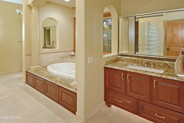 bathroom with tile patterned flooring, a tub to relax in, vanity, and decorative columns