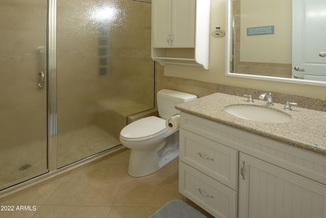 bathroom featuring vanity, tile patterned floors, toilet, tile walls, and a shower with shower door