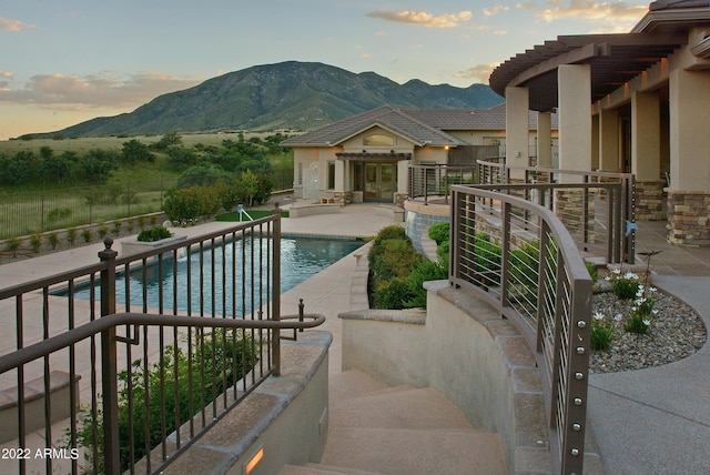 pool at dusk with a mountain view, a patio area, and a wall unit AC