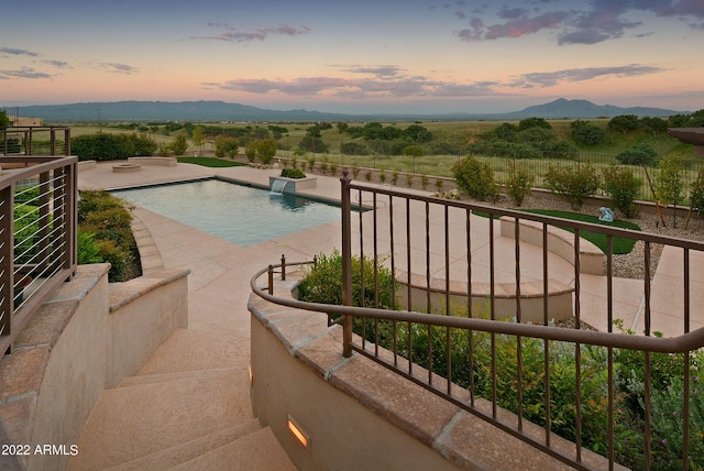 pool at dusk with a mountain view and a patio