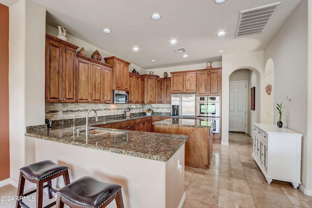 3660 S Golden Eye Ln, Gold Canyon, AZ 85118 - kitchen with stainless steel appliances, a sink, arched walkways, visible vents, and brown cabinets