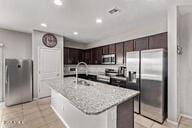 2614 S 120th Ave, Avondale, AZ 85323 - kitchen with stainless steel appliances, dark brown cabinets, a kitchen island with sink, a sink, and recessed lighting