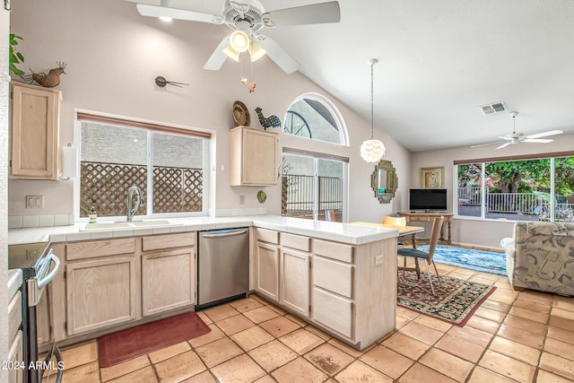 kitchen with a wealth of natural light, sink, tile counters, kitchen peninsula, and stainless steel appliances