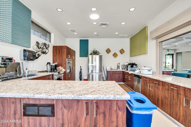 kitchen featuring a center island, appliances with stainless steel finishes, light stone countertops, and sink