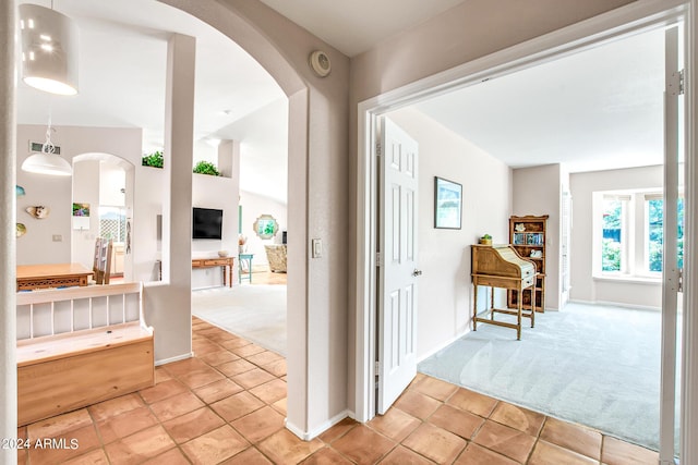 hallway featuring vaulted ceiling and light carpet