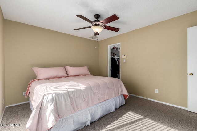 bedroom with carpet, ceiling fan, a spacious closet, a textured ceiling, and a closet