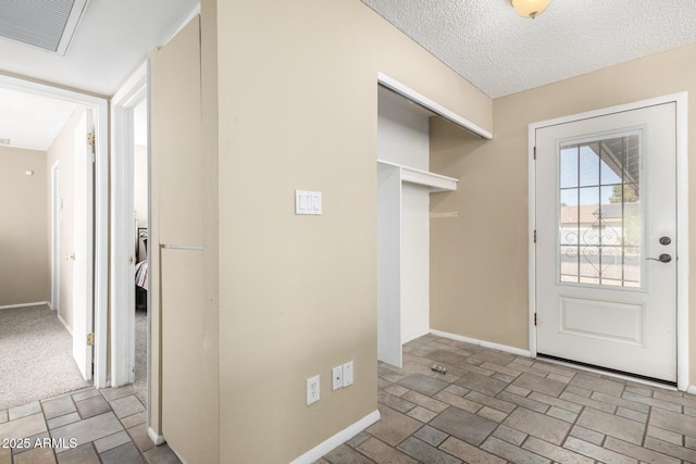 entrance foyer with light colored carpet and a textured ceiling