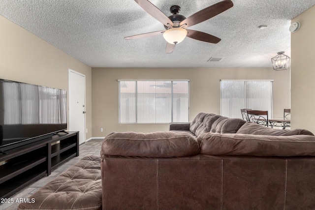 tiled living room with ceiling fan with notable chandelier and a textured ceiling