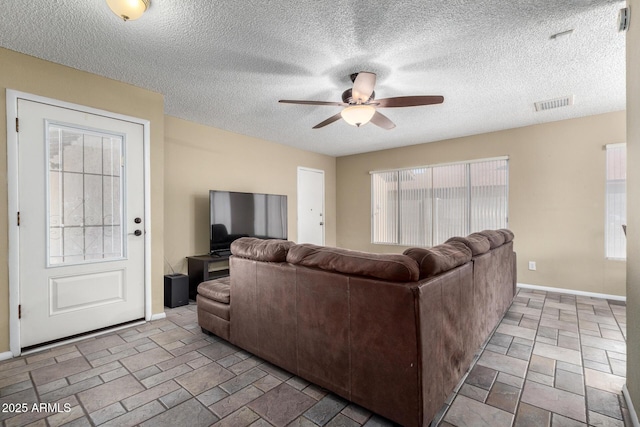 living room featuring ceiling fan and a textured ceiling