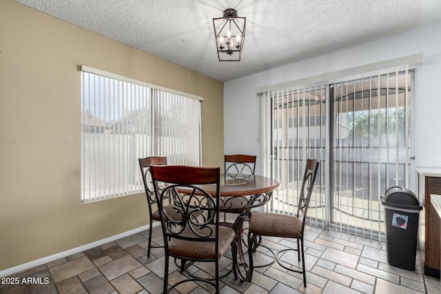 dining space with a textured ceiling and an inviting chandelier