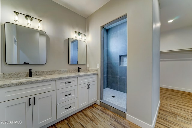 22009 W Montgomery Rd, Wittmann, AZ 85361 - bathroom with wood finished floors, tiled shower, double vanity, and baseboards