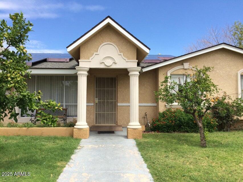 3116 W Dailey St, Phoenix, AZ 85053 - view of front of house with roof mounted solar panels, stucco siding, a front yard, and a shingled roof
