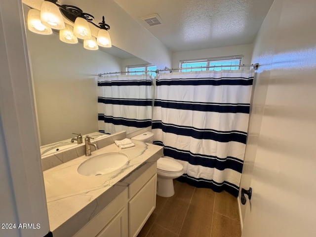 bathroom with a shower with curtain, vanity, toilet, and a textured ceiling